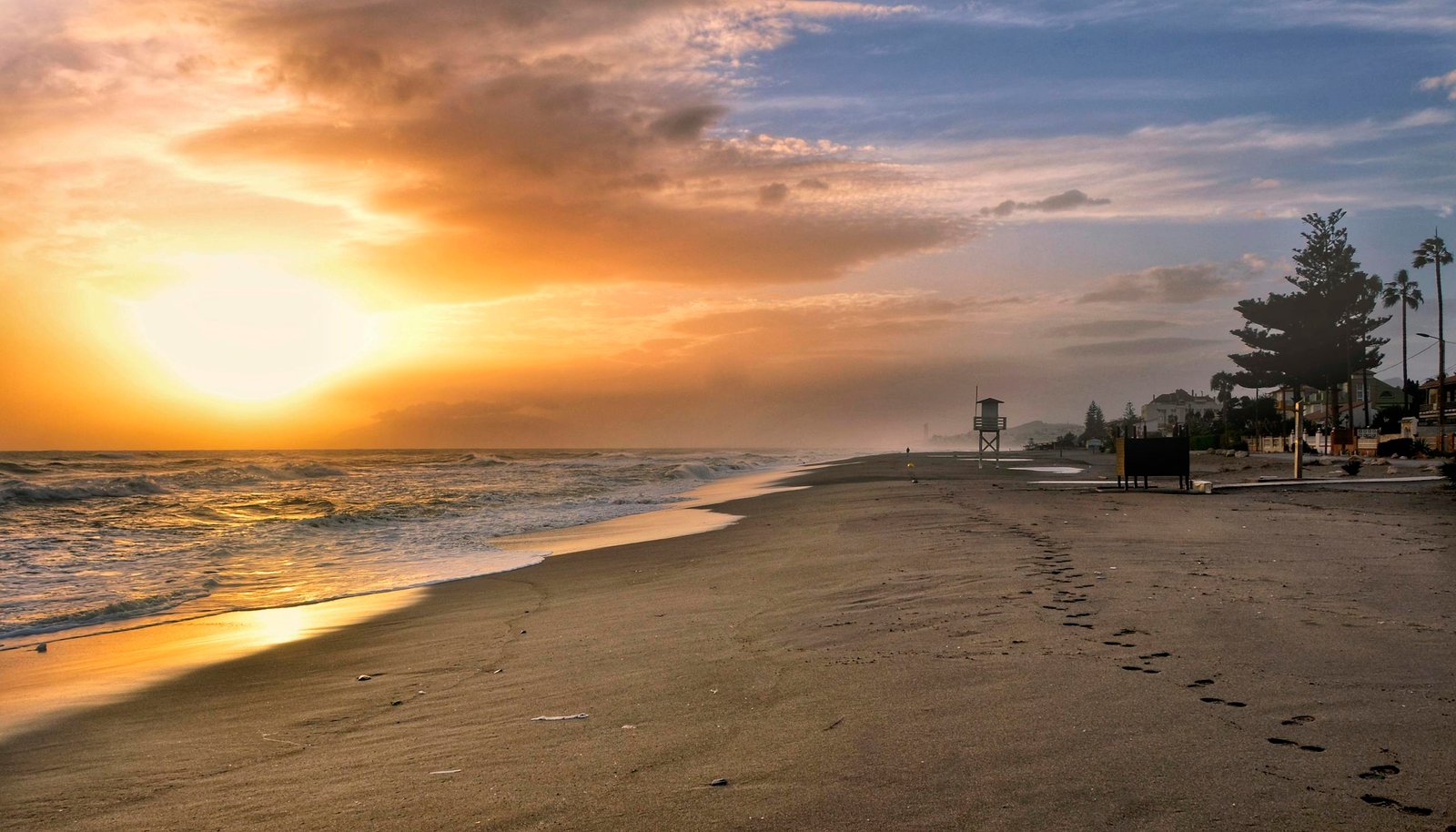 Beautiful sunset at Torre de Benagalbón beach with golden light reflecting on the shore.